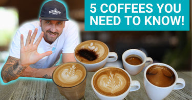 A picture of Jimmy Evans who is an Australian Coffee Expert holding his hand up showing 5 fingers and in front of him are 5 coffees that he shows how to make in his video. A latte, a flat white, a cappuccino, a long black and an espresso. 