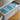 Bulk box of 72 Champion coffee drip bags with teal and white packaging on a wooden stool.
